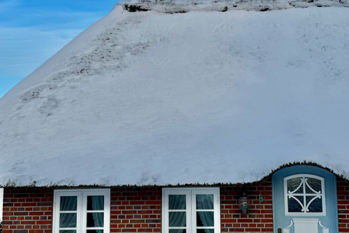 Reetdachhaus auf Sylt mit schneebedecktem Dach im Winter